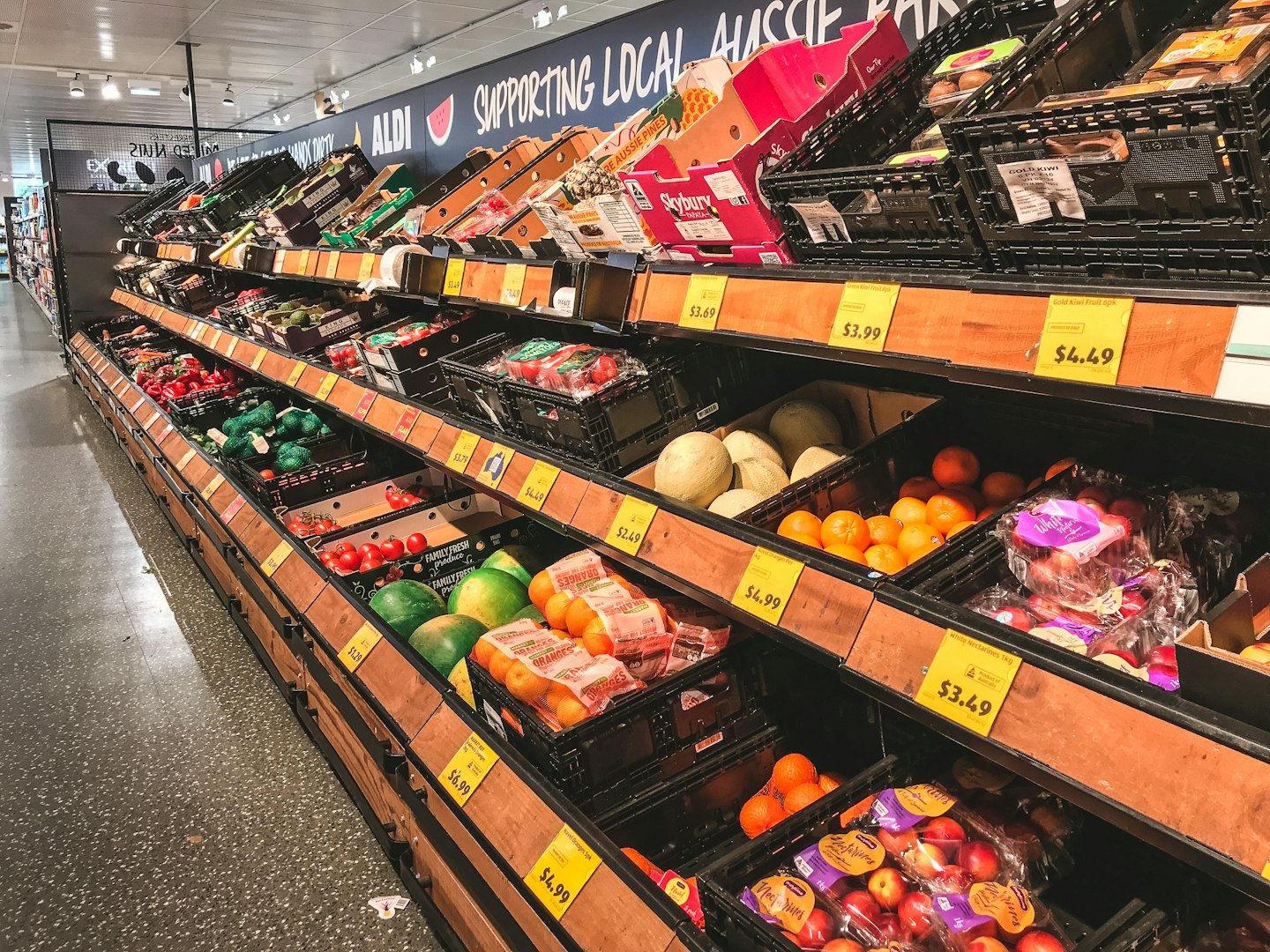 Bright supermarket aisle filled with fresh fruits and vegetables.