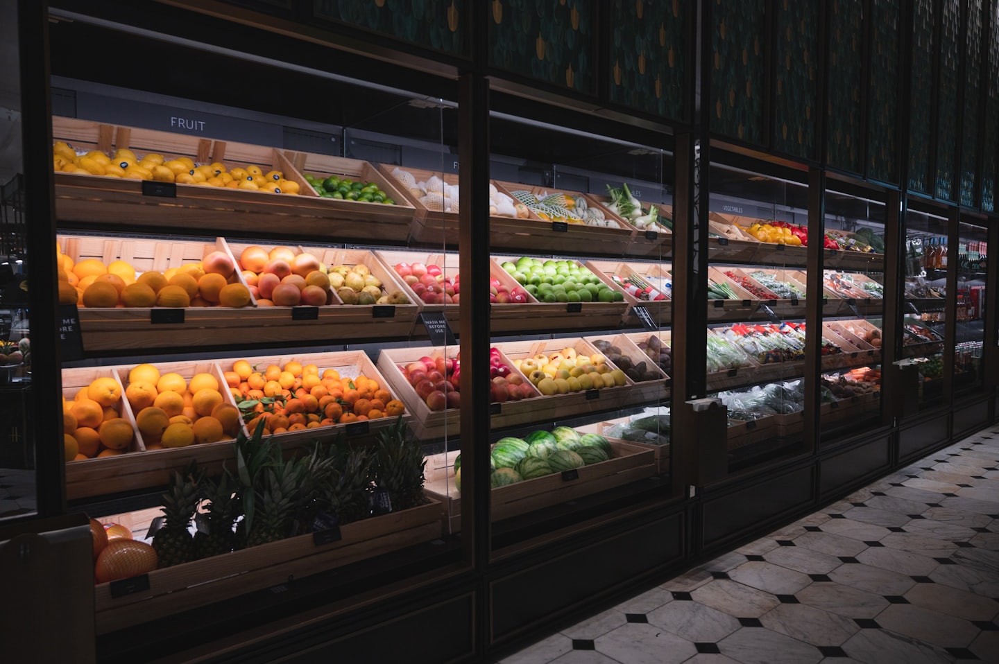 Wooden crates filled with fresh fruit and vegetables in supermarket display cases.