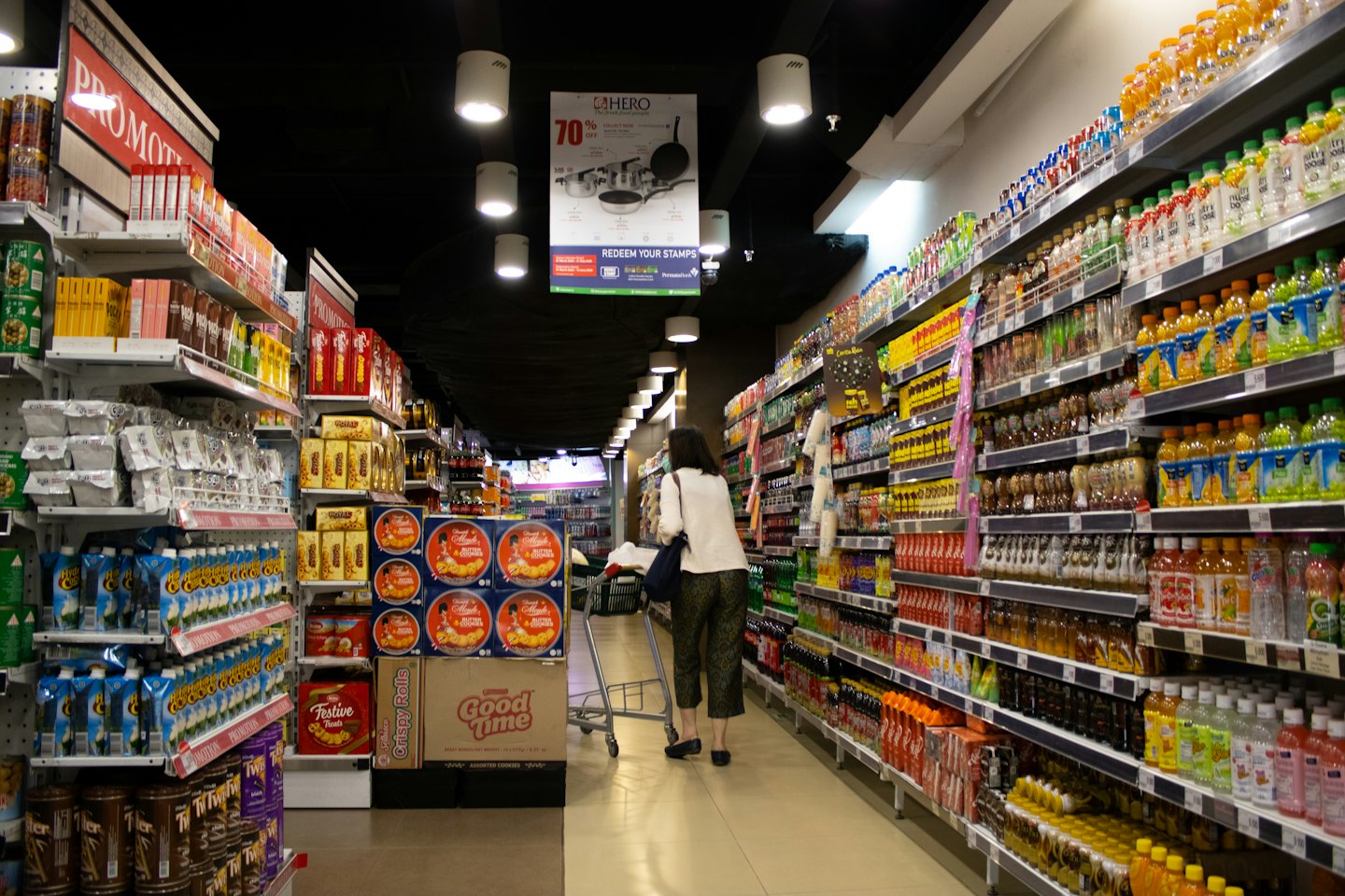 Shopper examines products on a grocery store shelf.