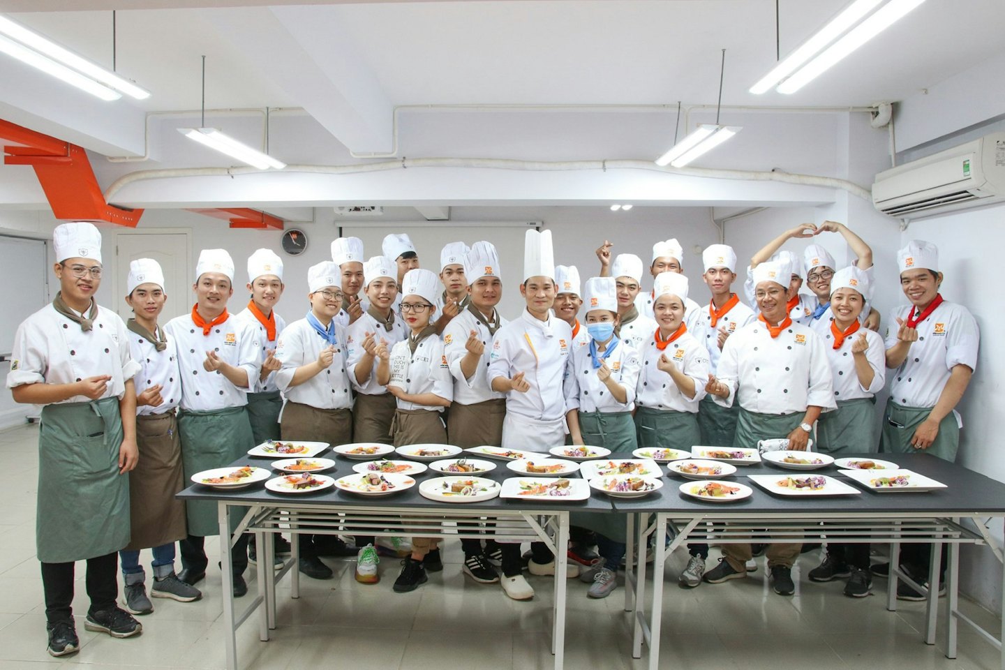 Culinary students and instructor smiling behind a display of plated food.