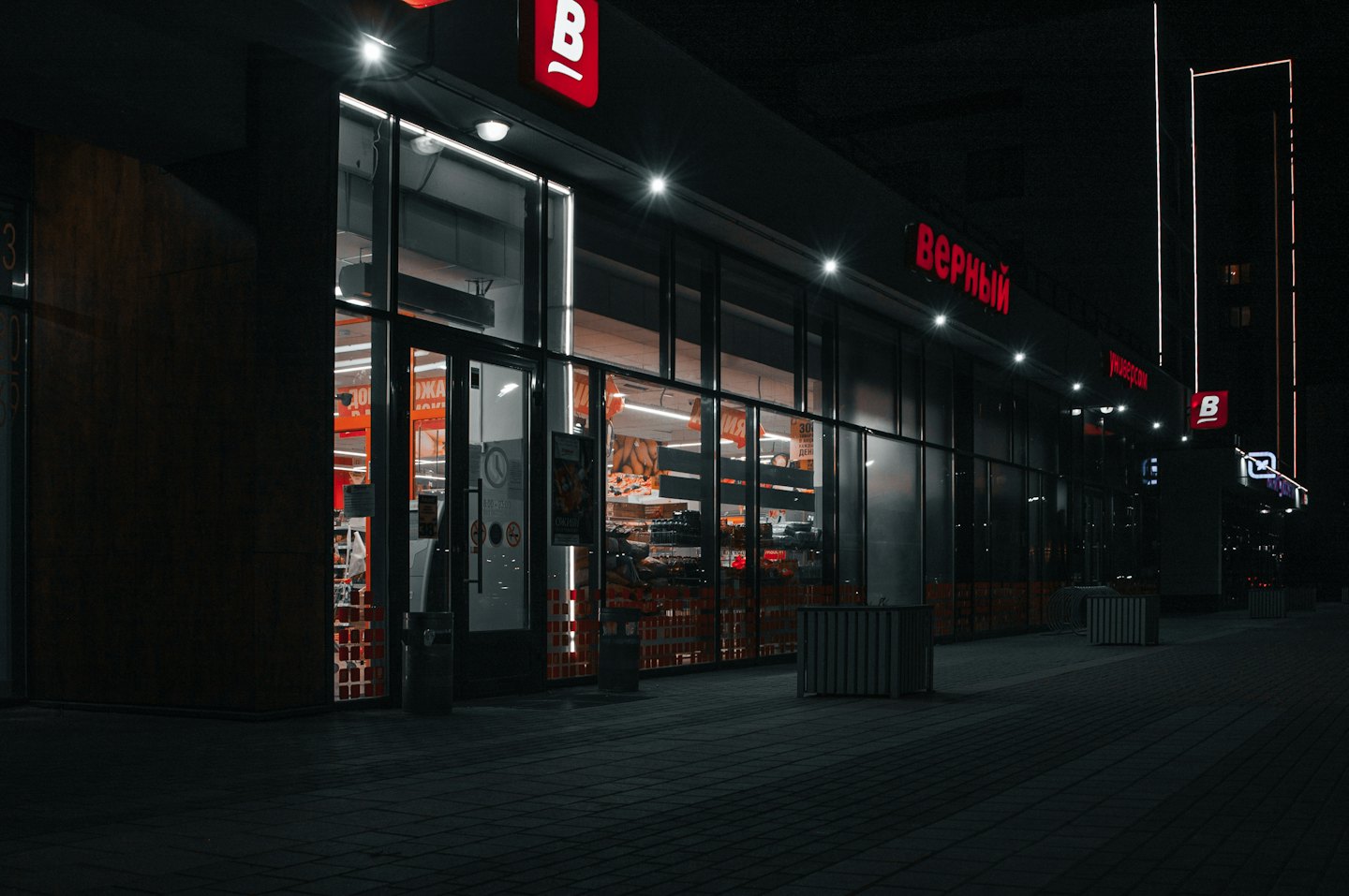 Modern supermarket with glass windows showing products on store shelves.